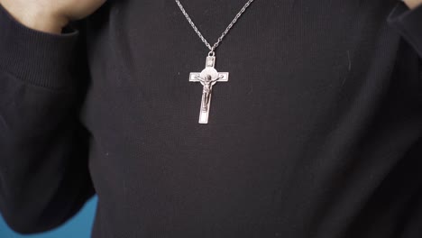 Close-up-Christian-man-hangs-cross-necklace-around-his-neck.